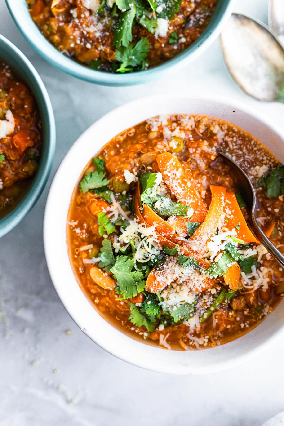 bowl of sausage and quinoa stew with spoon in soup