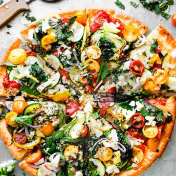 Overhead view veggie topped flatbread pizza, cut into slices.