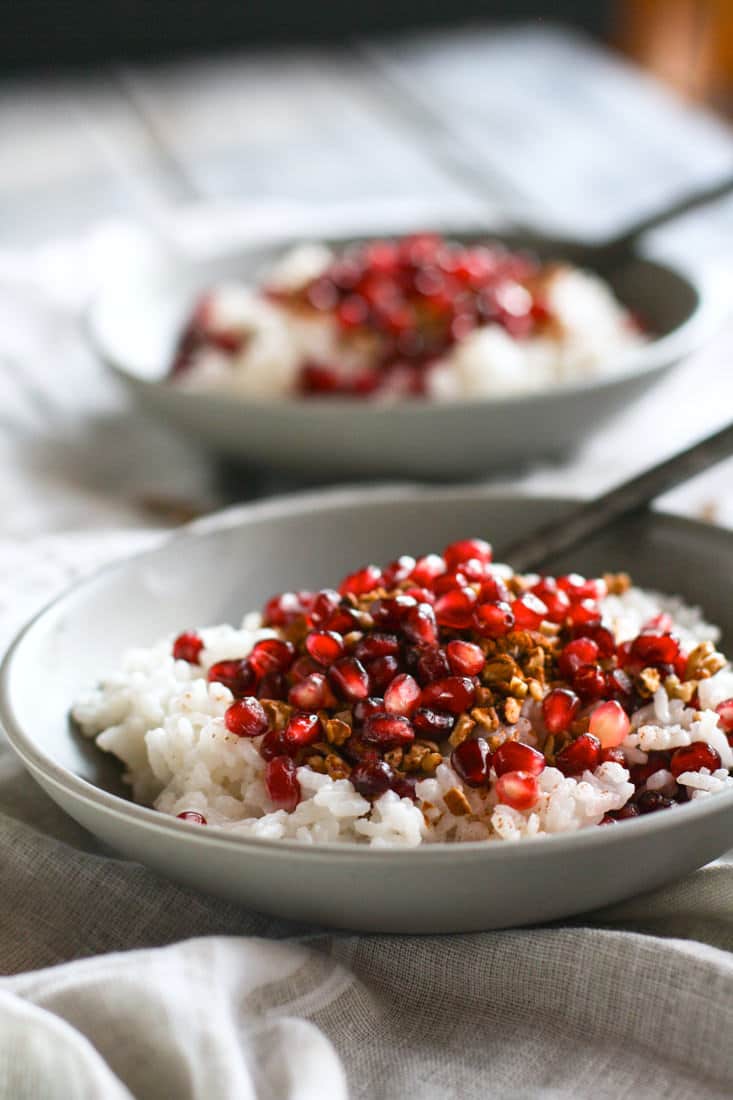 Coconut Rice and Pomegranate Porridge! Good carbs do exist! This gluten free and dairy free breakfast porridge makes for great performance fuel! A nourishing dish made with jasmine rice, coconut milk or cream, cinnamon, maple syrup, nuts, and cinnamon. The perfect combo of nutrient dense foods.
