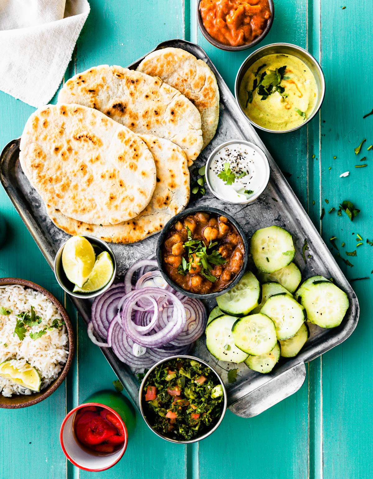 Grain free naan bread on silver baking sheet with topping fixings in small bowls around tray.