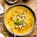 Overhead view chai turmeric smoothie bowl served in brown speckled bowl topped with chia seeds and oats.