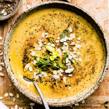 Overhead view chia spiced turmeric smoothie bowl served in brown speckled bowl topped with chia seeds and oats.