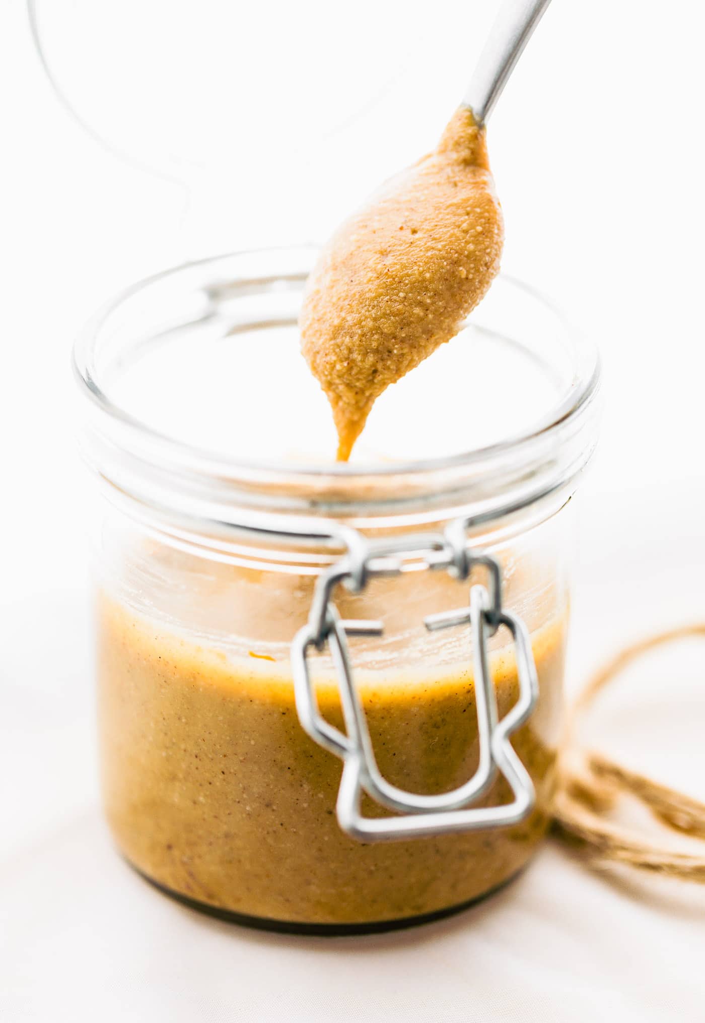 A spoonful of homemade cashew butter over a jar of nut butter.