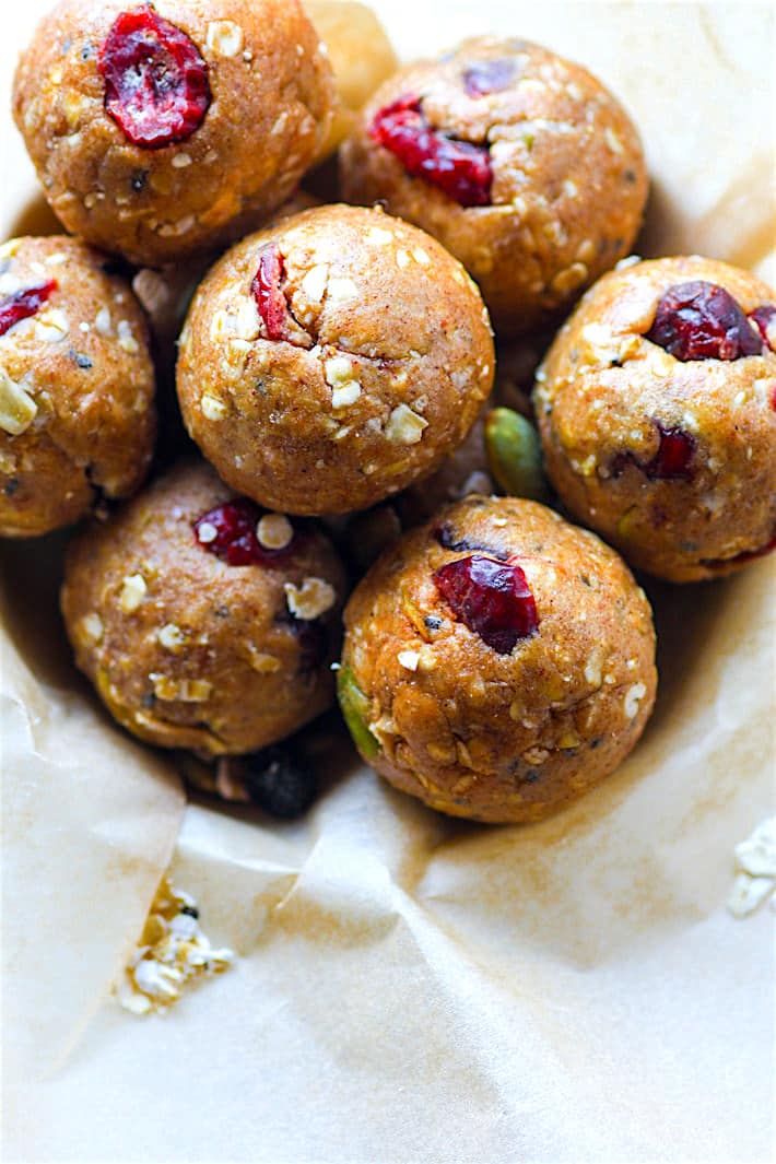 Several gluten-free muesli energy bites rolled to bite-size piled high in a parchment-covered bowl