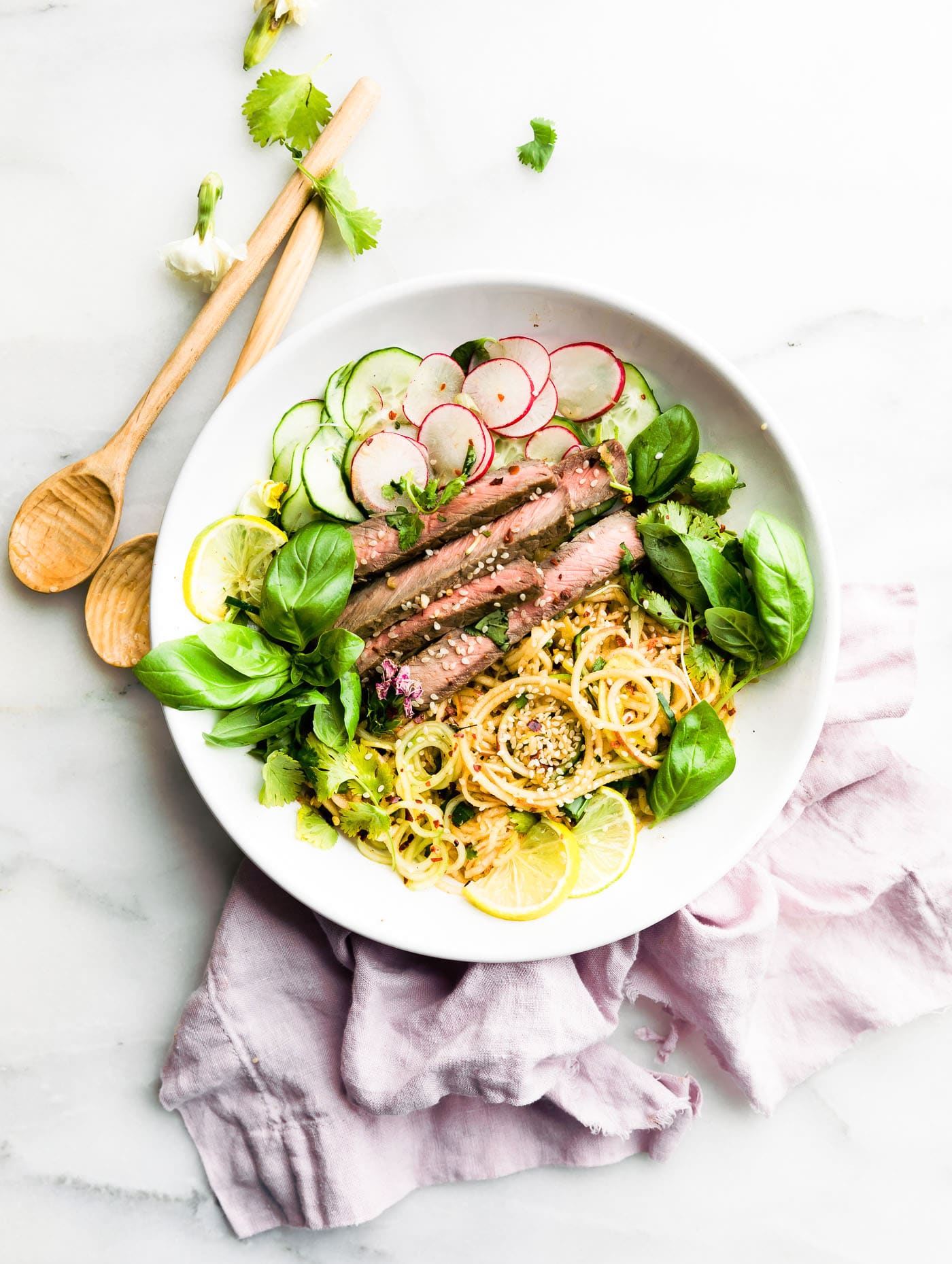 White shallow bowl filled with apple kimchi salad with strips of beef
