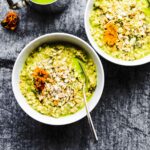 Two white bowls filled with matcha green tea latte oatmeal, topped with rolled oats and chia seeds.
