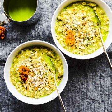Matcha green tea latte oatmeal in two white bowls topped with rolled oats and chia seeds.
