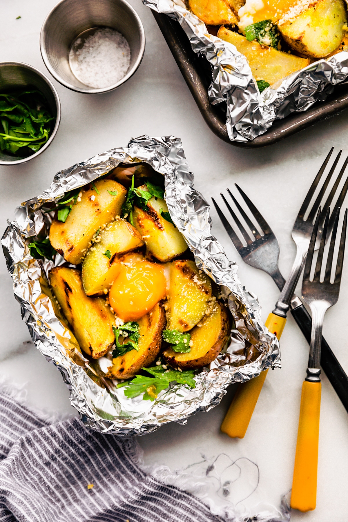 aluminum foil packet filled with potatoes and eggs on a dinner table