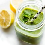 Overhead view green smoothie in mason jar cup topped with fresh mint and polka dot straw