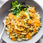 Chili garlic cauliflower risotto bowl topped with orange sauce.