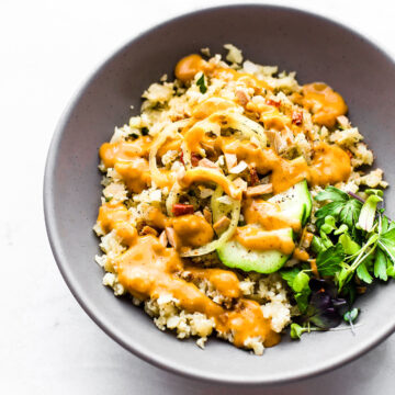 Chili garlic cauliflower risotto served in bowl topped with orange sauce.