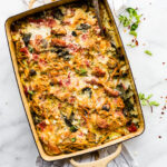 serving spoon in a kale pesto sweet potato spaghetti casserole
