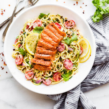 Cajun Smoked Salmon Pasta Salad served in a white bowl with cilantro and a lemon wedge as garnish