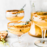 Side view several glasses with sugared rims filled with honey roasted pear sparkling cockails.