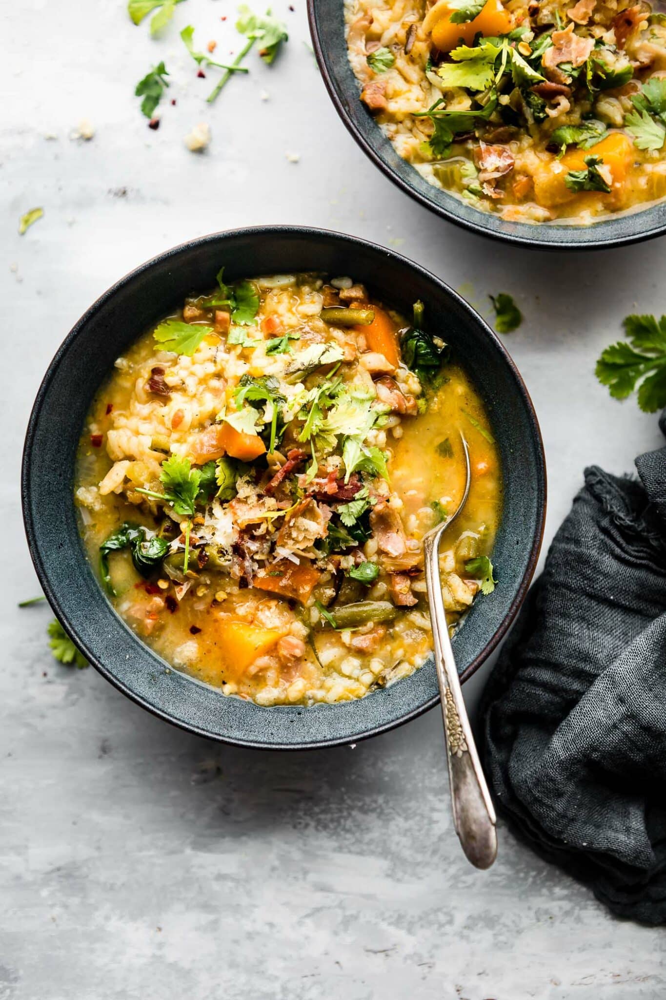 Two bowls filled with Everything But the Kitchen Sink soup, topped with fresh herbs.