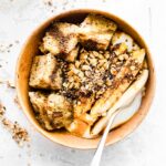 Overhead view sticky date cake yogurt bowl with silver spoon in yogurt.