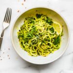 Overhead view roasted poblano pesto zucchini noodles on stone plate.