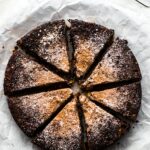 Overhead photo of gluten free chocolate Christmas cake cut into slices and dusted with sugar.
