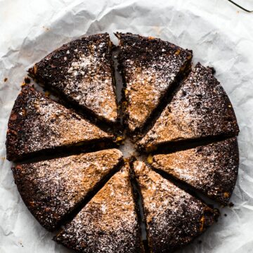 Overhead photo of gluten free chocolate Christmas cake cut into slices and dusted with sugar.