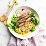 Overhead view white plate filled with serving of spiralized apple kimchi with beef strips.
