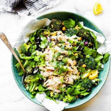 Overhead view turquoise bowl filled with no mayo chicken salad over mixed greens and broccoli