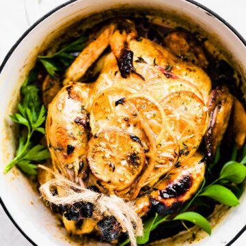 Overhead view roasted whole chicken with orange honey garlic glaze in pot.