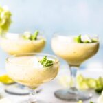 Three short wine glasses filled with frozen mint melon wine cocktail garnished with mint