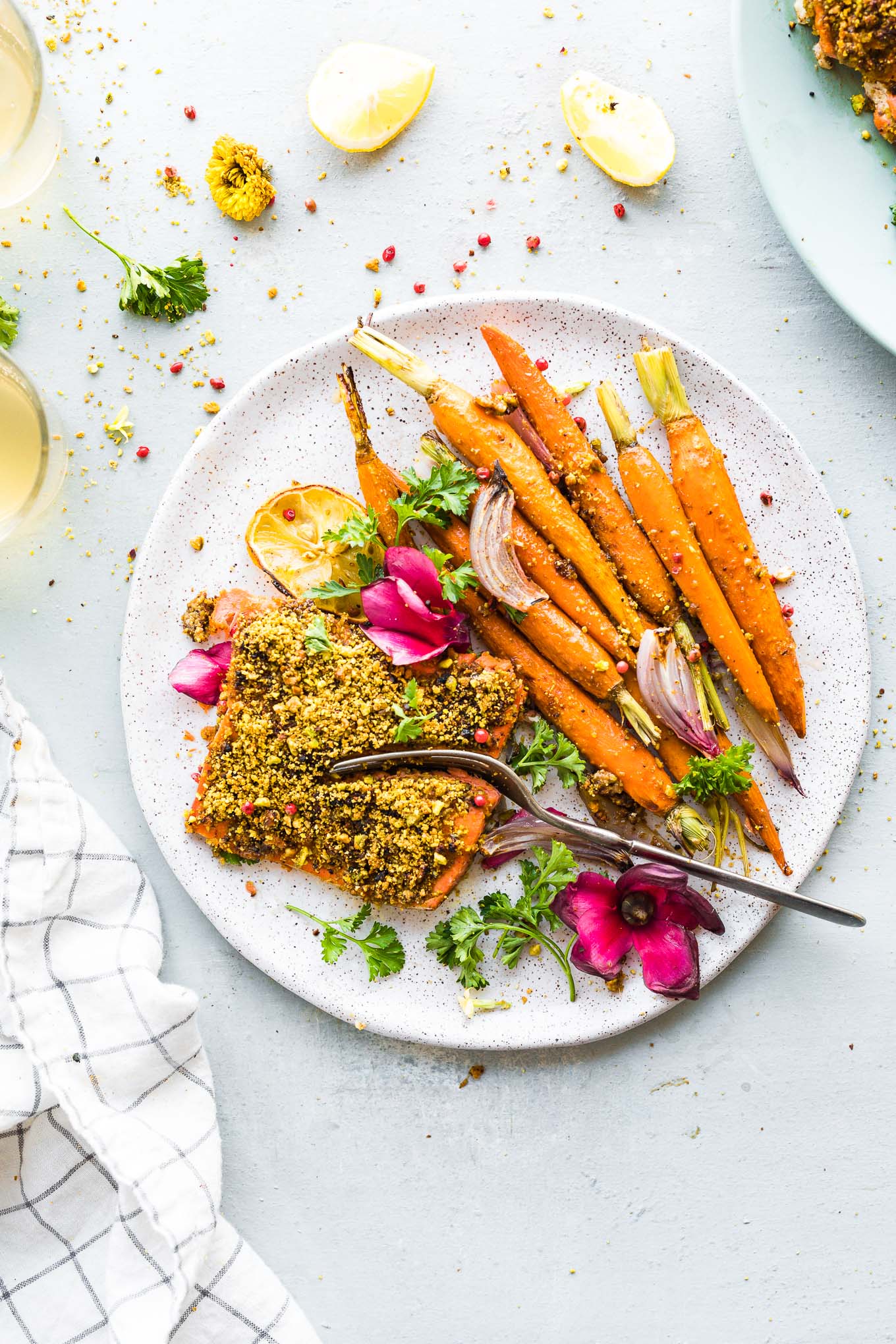 plate of pistachio crusted salmon with glazed carrots, fork cutting into salmon fillet.