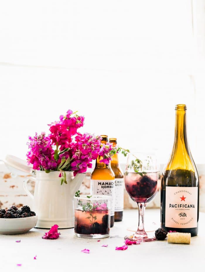 Wine bottles, floral arrangements and glasses of mixed drinks on white table