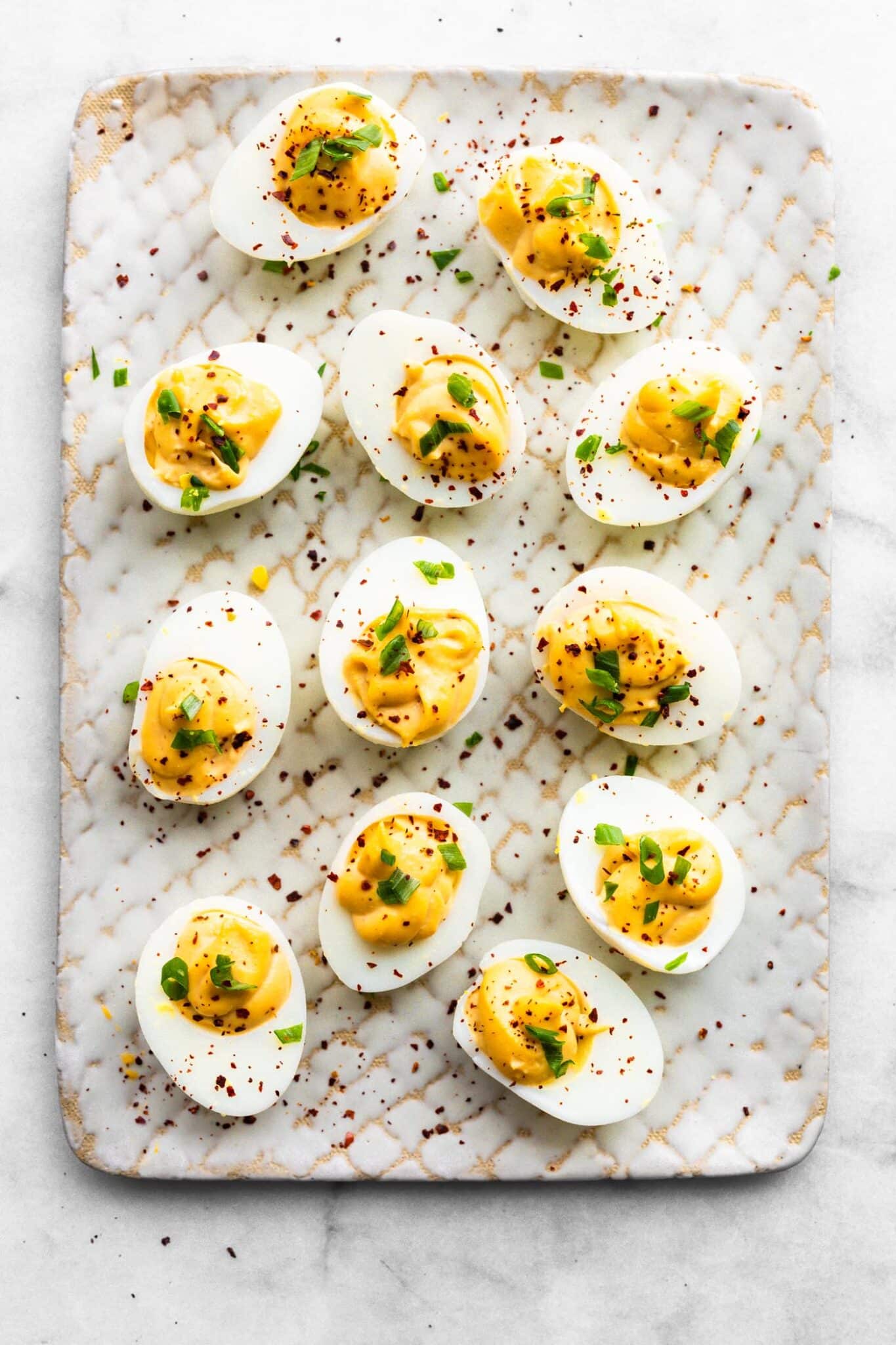 White platter filled with spicy chipotle deviled eggs topped with fresh herbs.