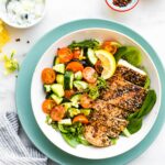 Turquoise rimmed bowl filled with Za'atar Chicken Bowls with Tomato and Cucumber Raita