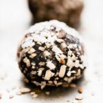 a coconut chocolate protein ball topped with coconut flakes