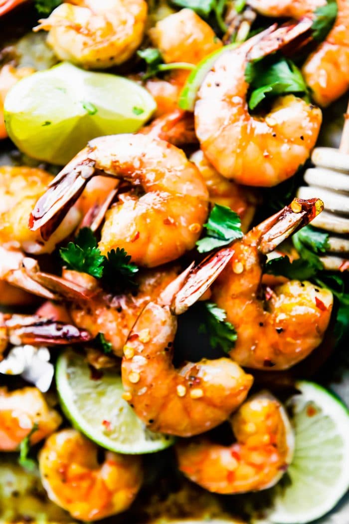 plate of tail-on baked shrimp surrounded by lime slices