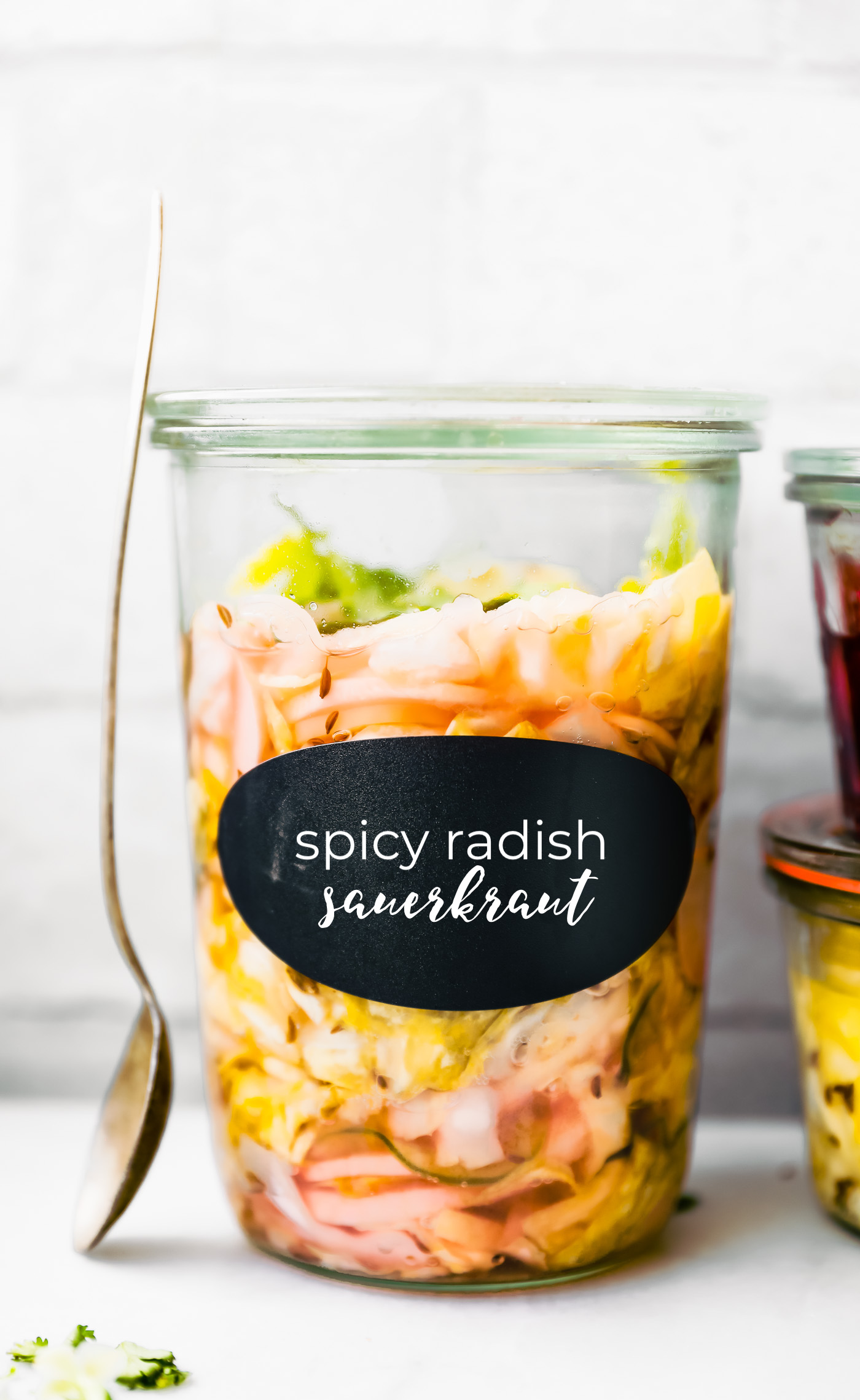 Close up side view jar of homemade sauerkraut with black label on jar with 'spicy radish sauerkraut' on label.