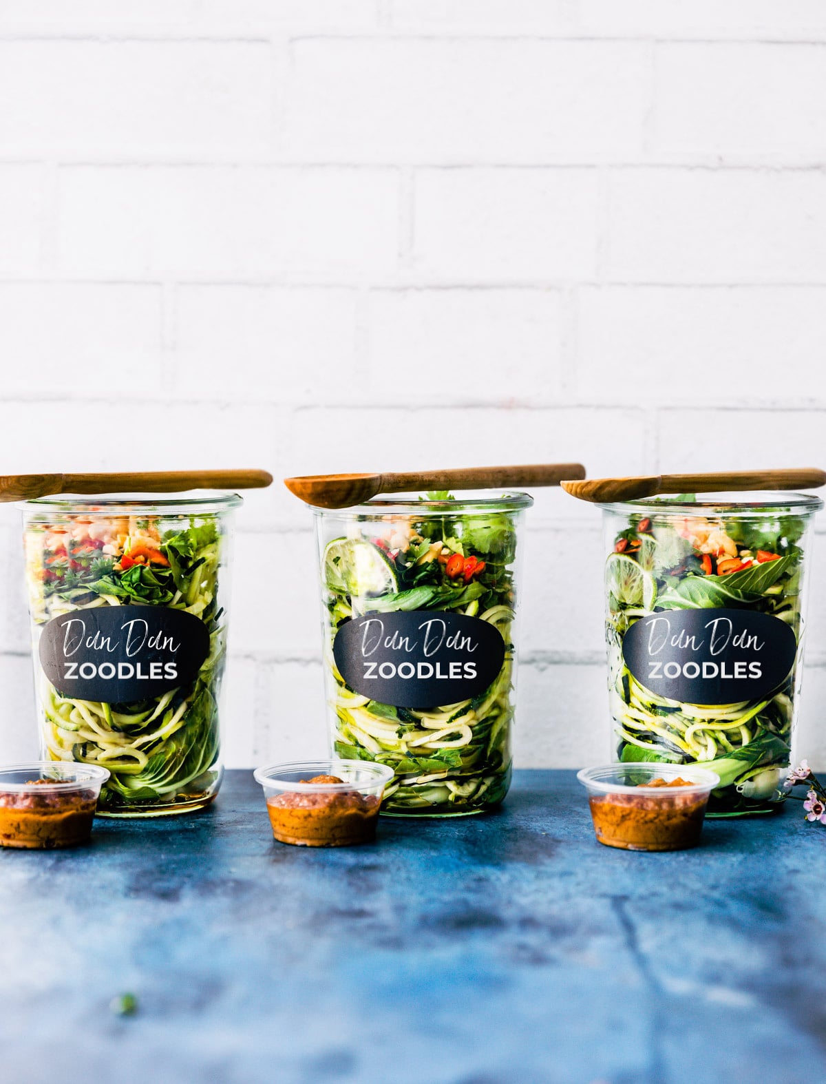 Three Weck jars filled with Dandan noodles and toppings, wooden spoon resting on top of each jar