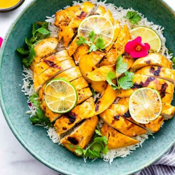 overhead photo: mango chile chicken breasts on a bed of cauliflower rice in green serving bowl