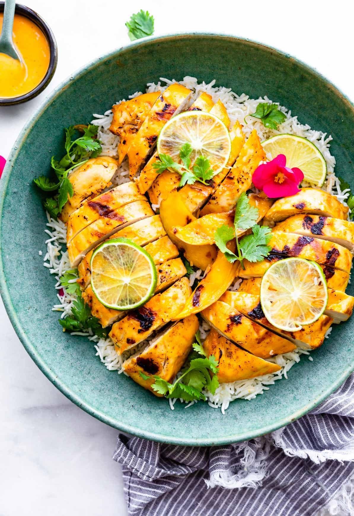 overhead photo: mango chile chicken breasts on a bed of cauliflower rice in green serving bowl