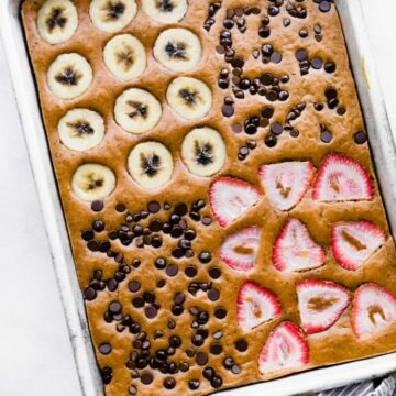 sheet pan keto pancakes with toppings of sliced bananas, strawberries, and chocolate chips