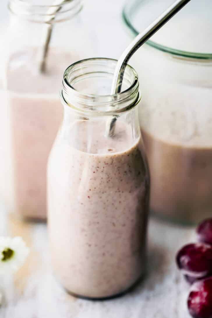 frozen smoothie with grapes and yogurt in 2 glasses with straws.