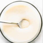 glass bowl of homemade sweetened condensed milk with spoon in it