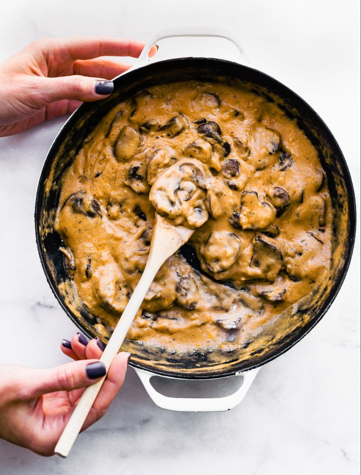Overhead photo of a wooden spoon in a pan of homemade vegan condensed cream soup.