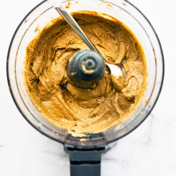 overhead: spoon in the bowl of a food processor, scooping creamy seed butter out