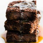 stack of 3 vegan brownies covered with salted caramel sauce
