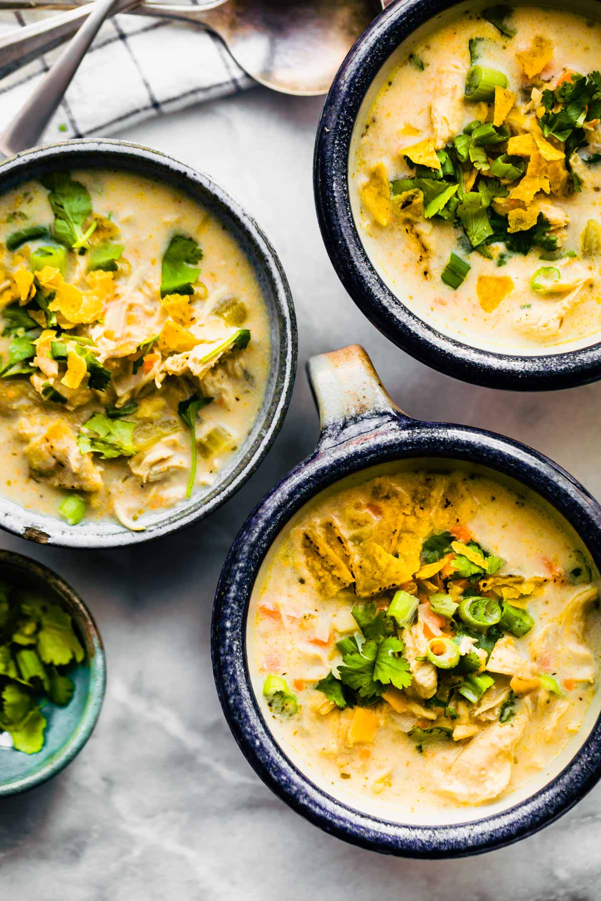 overhead: 3 bowls of Instant Pot White Chicken Chili garnished with fresh cilantro and scallions