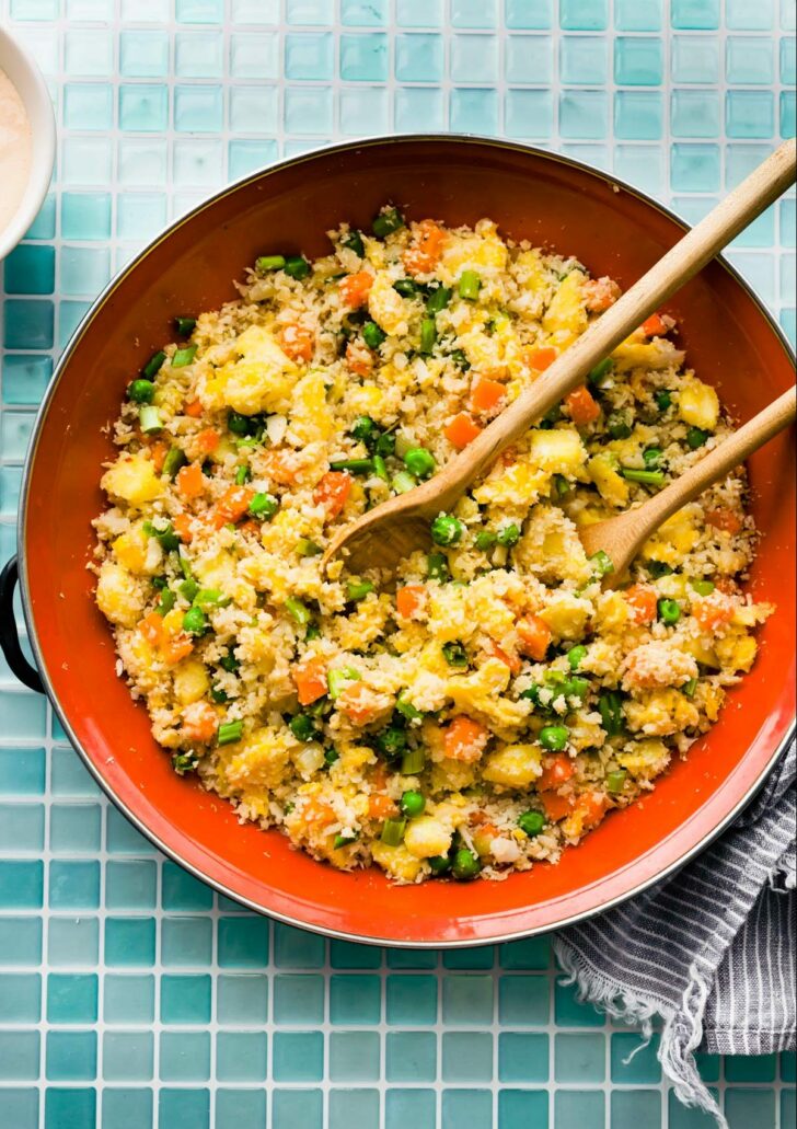overhead image: two serving spoons in skillet of homemade healthy fried rice