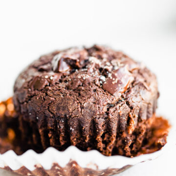 one fluffy gluten free chocolate muffin topped with sea salt on white paper cupcake liner