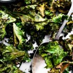 Detail shot of seasoned, crispy kale chips on a sheet pan