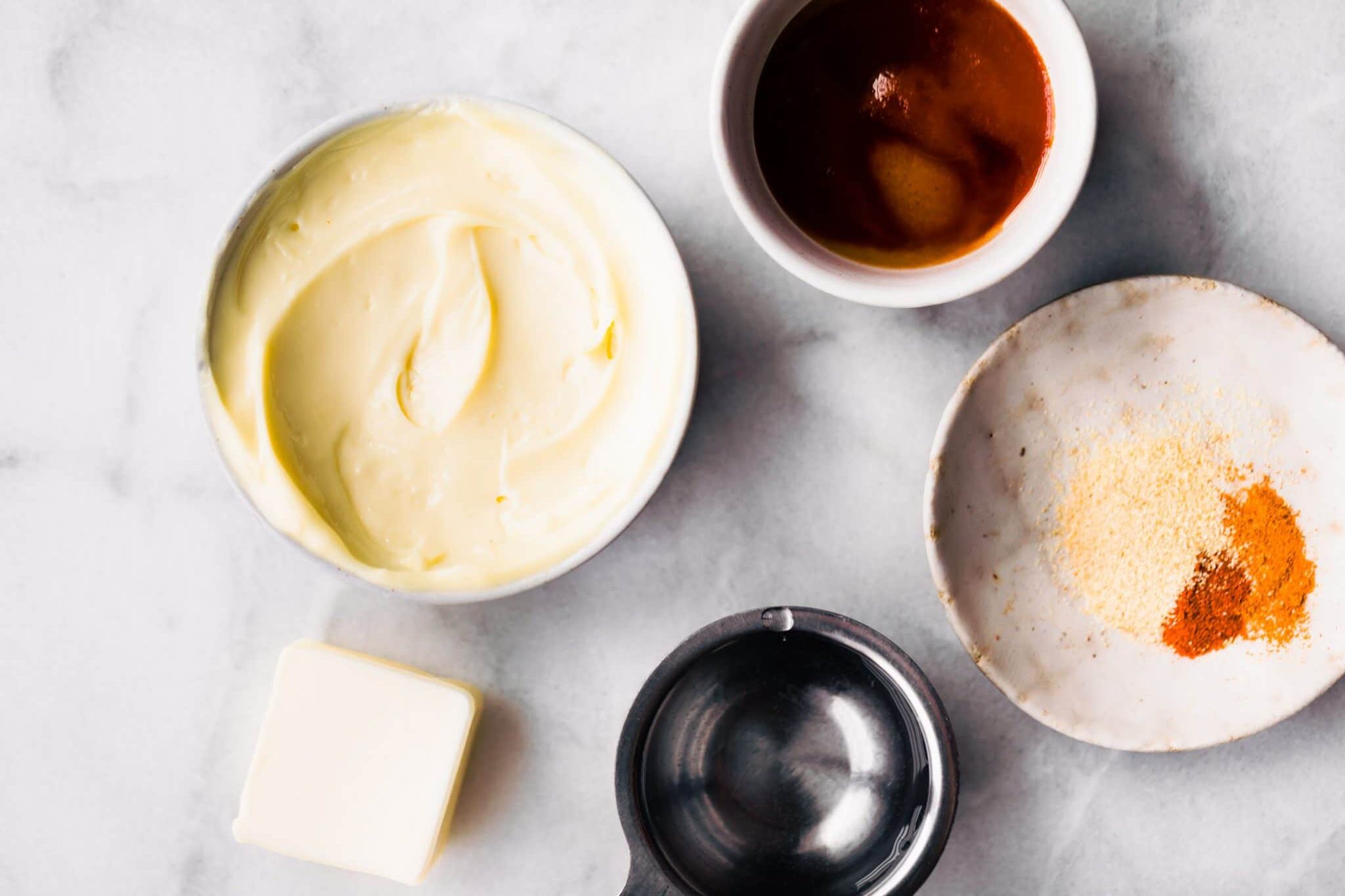 yum yum sauce ingredients in prep bowls: paleo mayo, maple syrup, ghee, and spices