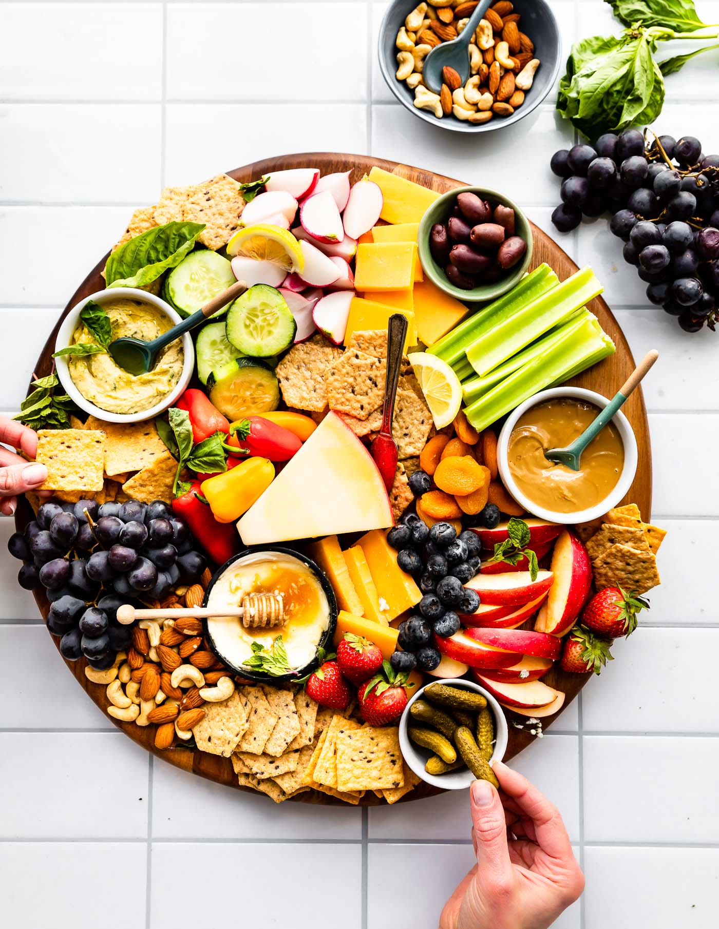 Overhead image of serving platter with crackers, vegetables, fruits, nuts, cheese, and dip.