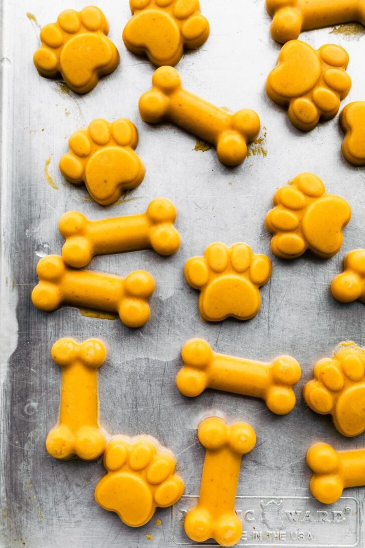 Homemde dog treats shaped as bones and paw prints on a baking sheet